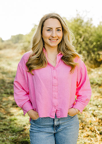 Angelina L., Marketing bei Supplera - Lächelnde Frau mit langen blonden Haaren in pinker Bluse in der Natur