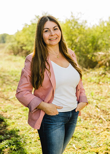 Christina K., Datenpflege bei Supplera - Lächelnde Frau in rosa Jacke vor grünem Hintergrund