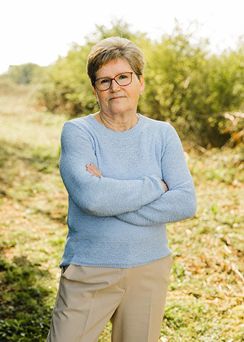 Christa L., Raumpflege bei Supplera - Ältere Frau mit Brille in hellblauem Pullover, die draußen steht