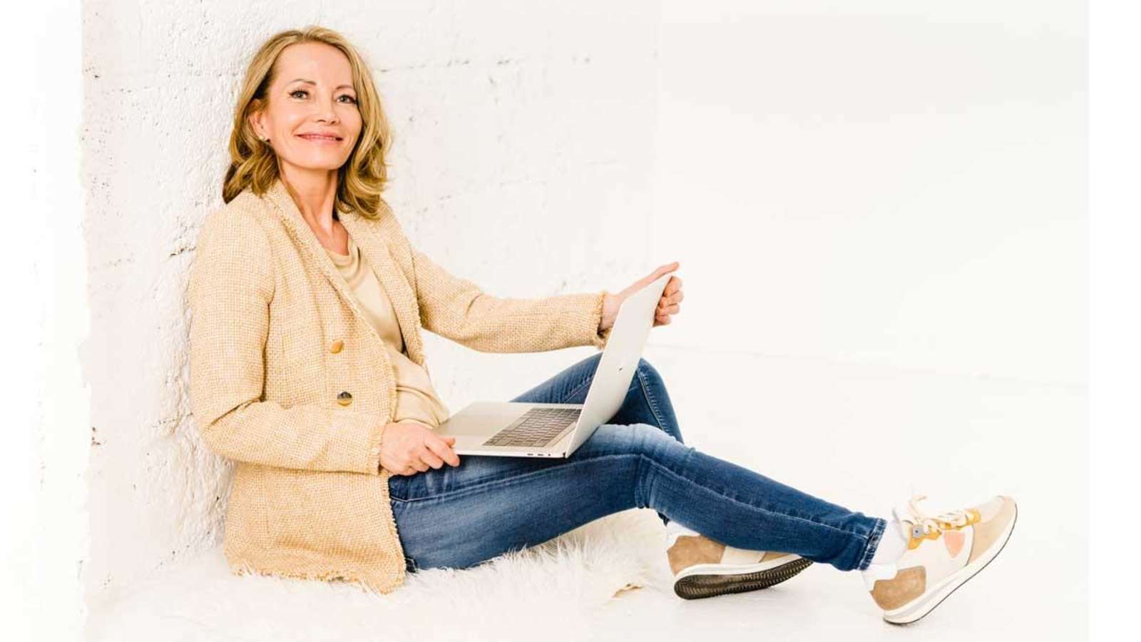 Martina Leukert, Mitgründerin von Supplera, mit Laptop vor heller Wand