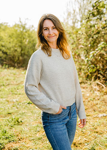 Svenja S., Marketing bei Supplera - Lächelnde junge Frau in beigefarbener Bluse vor hohen Gräsern