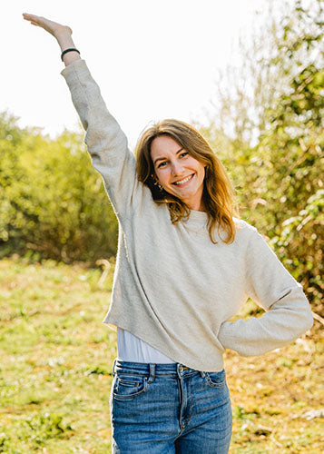 Svenja S., Marketing bei Supplera - Lächelnde junge Frau in beigefarbener Bluse vor hohen Gräsern